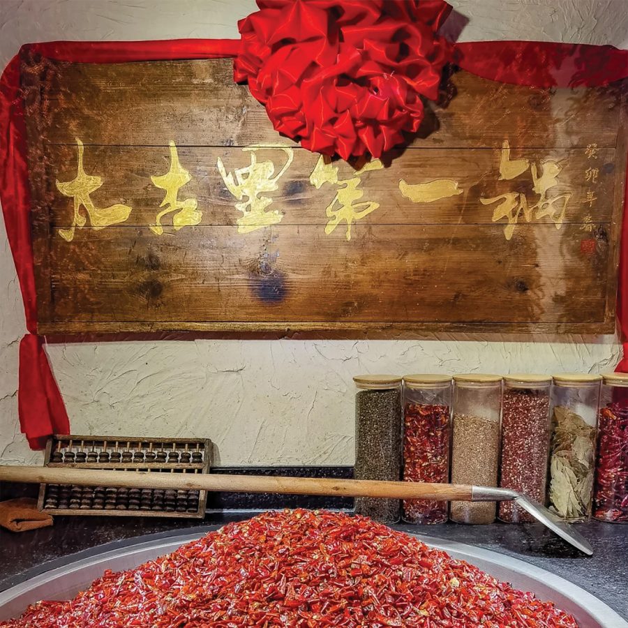 View of a brown wooden plaque hanging above spices at Jia Ling Ma Tou in Chengdu.