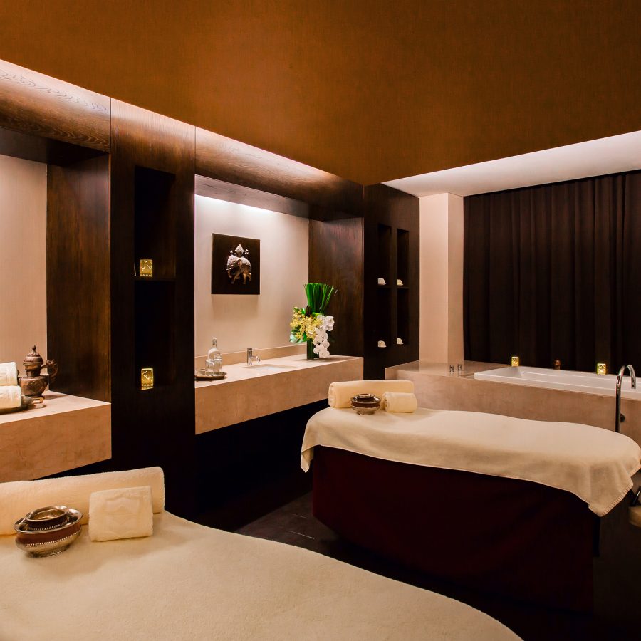 A spa treatment room at Shangri-La Sydney with drawn curtains features two beds and semi-wooden interiors.