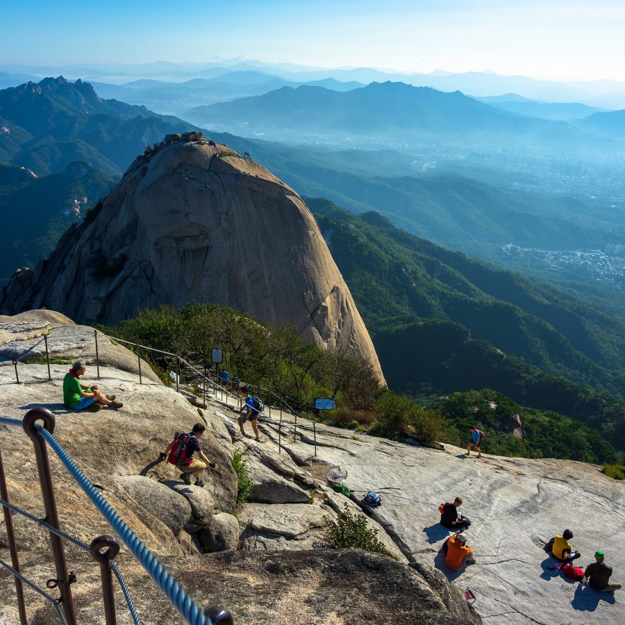 Hikers rest on a plateau at Bukhansan National Park in South Korea in the daytime.