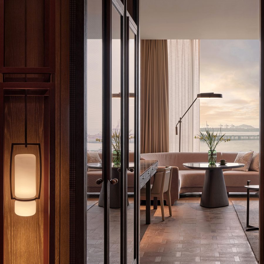 A guest room at Conrad Shenzhen features detailed wallpaper and a spacious living room looking out at the skyline of Qianhai.  