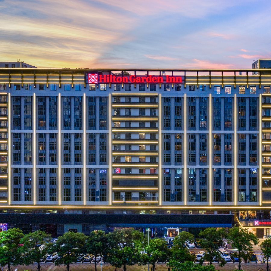 The exterior of Hilton Garden Inn in Shenzhen is a wide multi-storey building. 