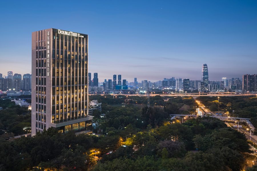 An aerial view of DoubleTree by Hilton Shenzhen Nanshan Hotel & Residences shows the foot of the property surrounded by forest. 