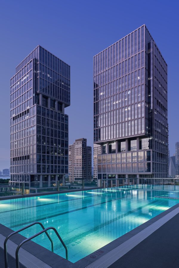 The exterior of JEN Shenzhen Qianhai by Shangri-La features two blocky buildings outfitted with a large outdoor pool.