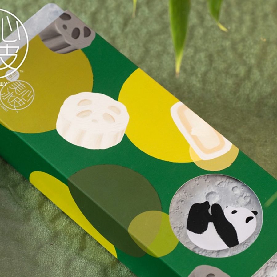 Product image of Maxim's Panda Snowy Duet Mooncake Gift Box, which has green packaging with pandas on it, placed next to a bamboo plant. 