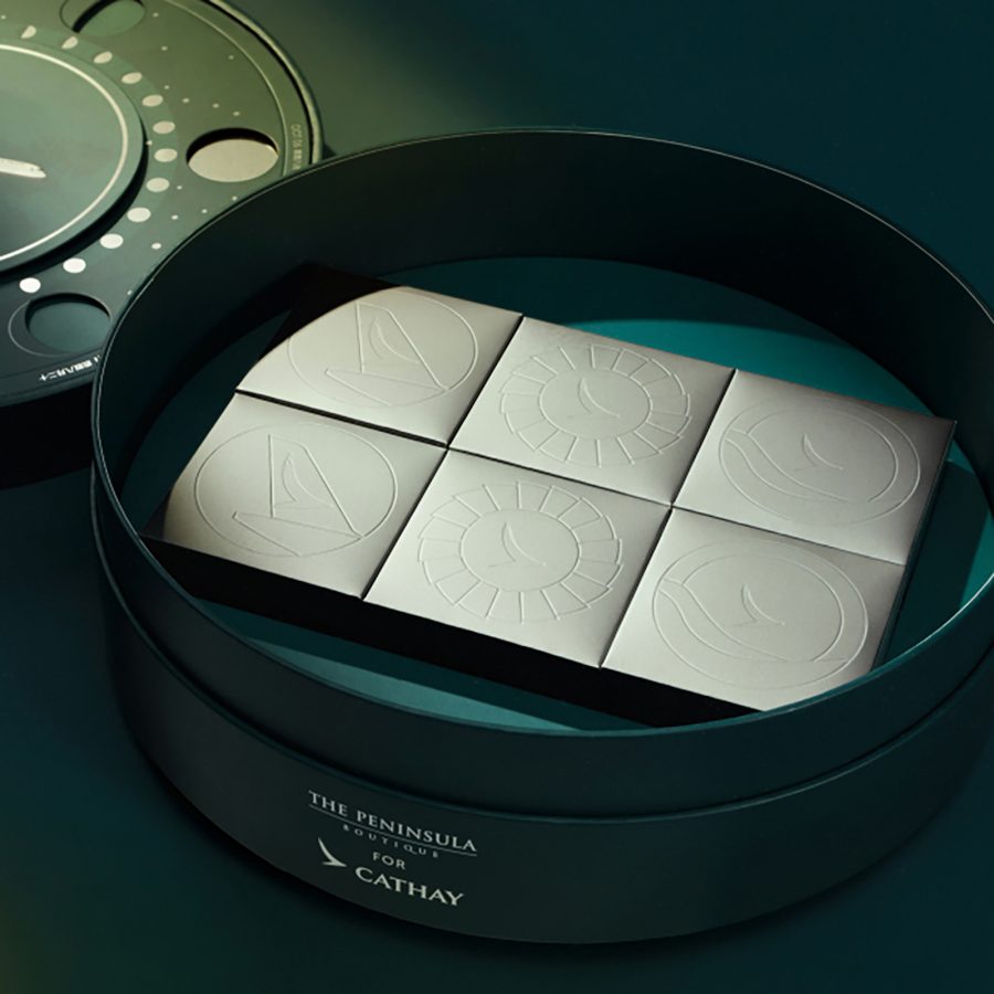 Product image of the Cathay x The Peninsula Boutique Assorted Mini Mooncakes, with the lid removed from the round keepsake box, showing the square mooncake boxes inside. 