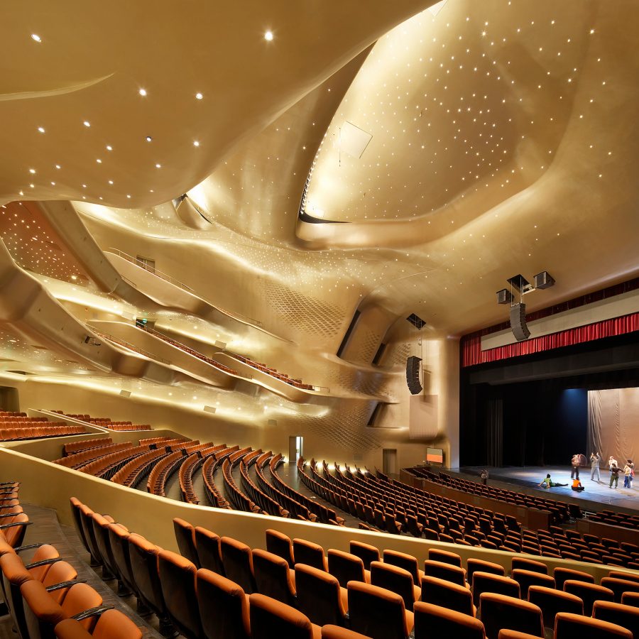 The interior of Guangzhou Opera House’s Opera Hall has a golden ceiling suspended over rows of seats.