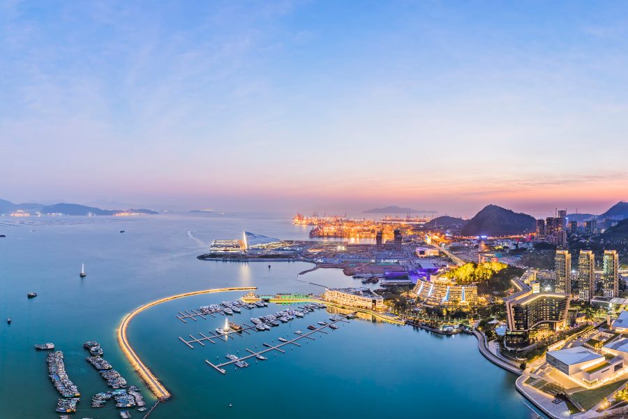 An aerial view of Shekou, Shenzhen shows the skyline and roads lit up in yellow light in the evening.