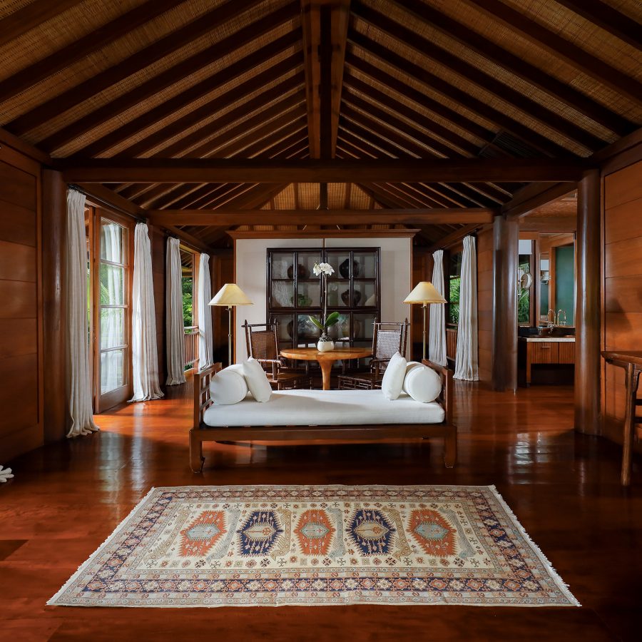 A white sofa is put in the middle of a wooden lodge at Como Shambhala Estate. 