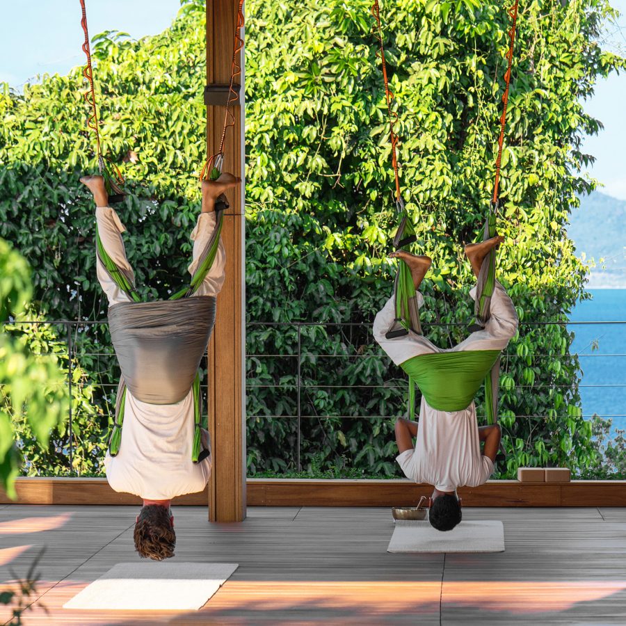 Guests hang upside down while looking out at the sea at Six Senses Krabey Island. 