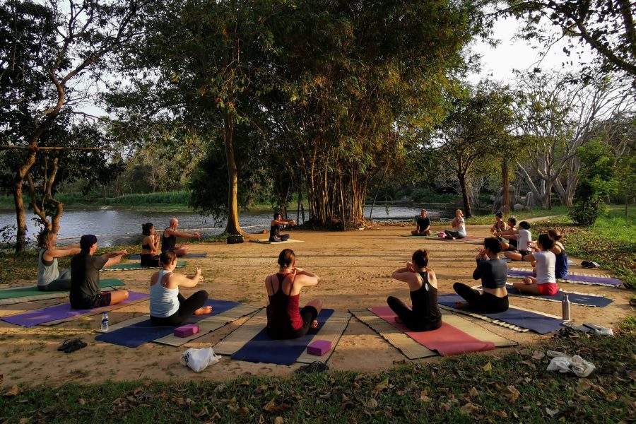  A group of guests sit on yoga mats in a circle in a semi-circle