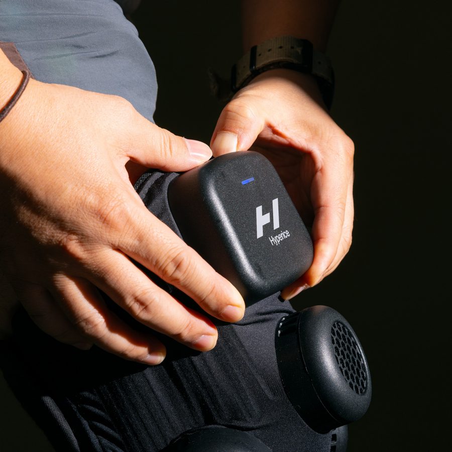 Close-up of the Hyperice X Knee when worn, with two hands placed on the device.