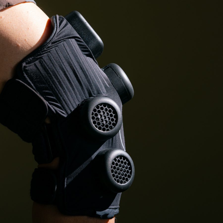 Side view of the Hyperice X Knee on a bent knee, showing the round module vents.