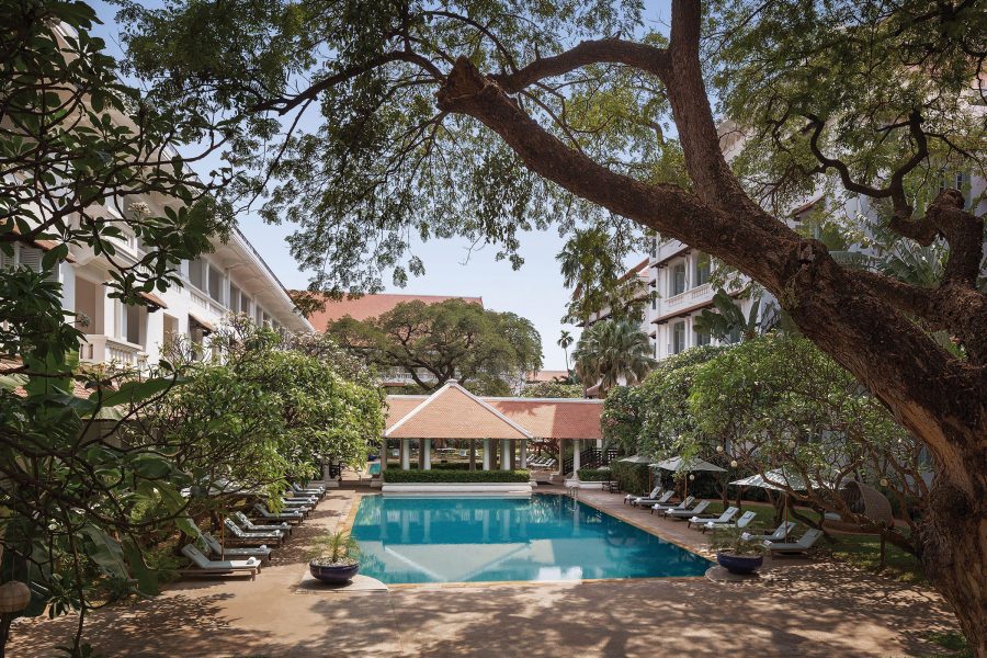 An outdoor pool sits beneath the shade of trees at Raffles hotel Le Royal Phnom Penh.