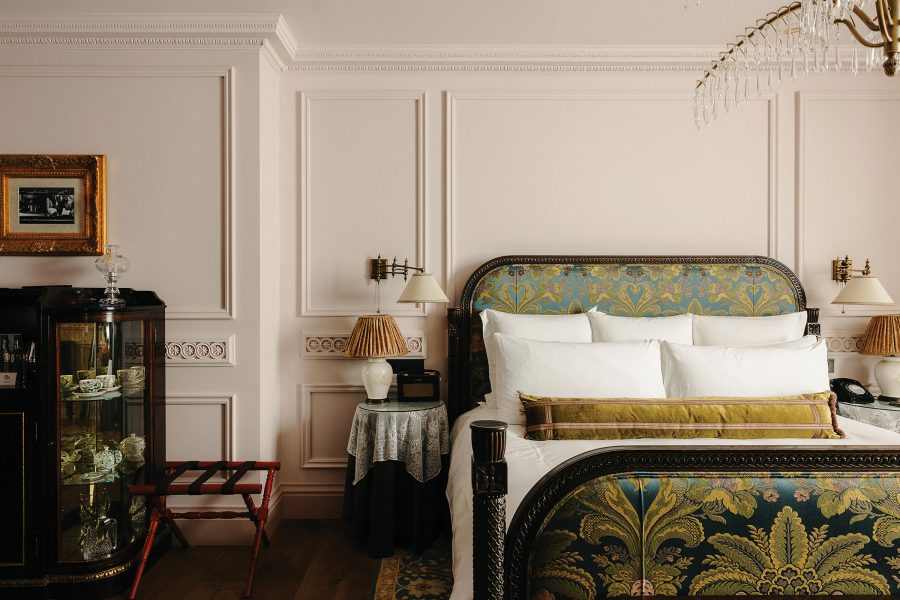 A view of a hotel room at The Ned London hotel with a beautifully decorated green and yellow bed.