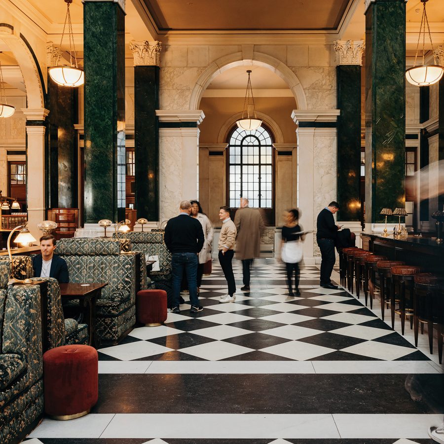 People walking through the main lobby of The Ned across black and white chequered floors