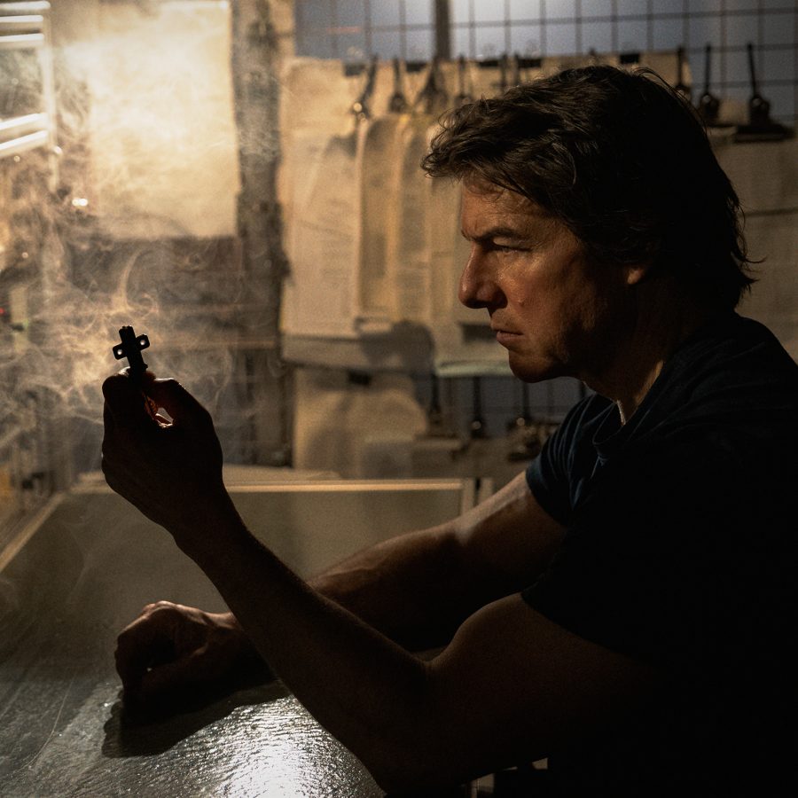 In a dark, dusty room, a man holds up a small artefact, in a scene from Mission: Impossible - The Final Reckoning