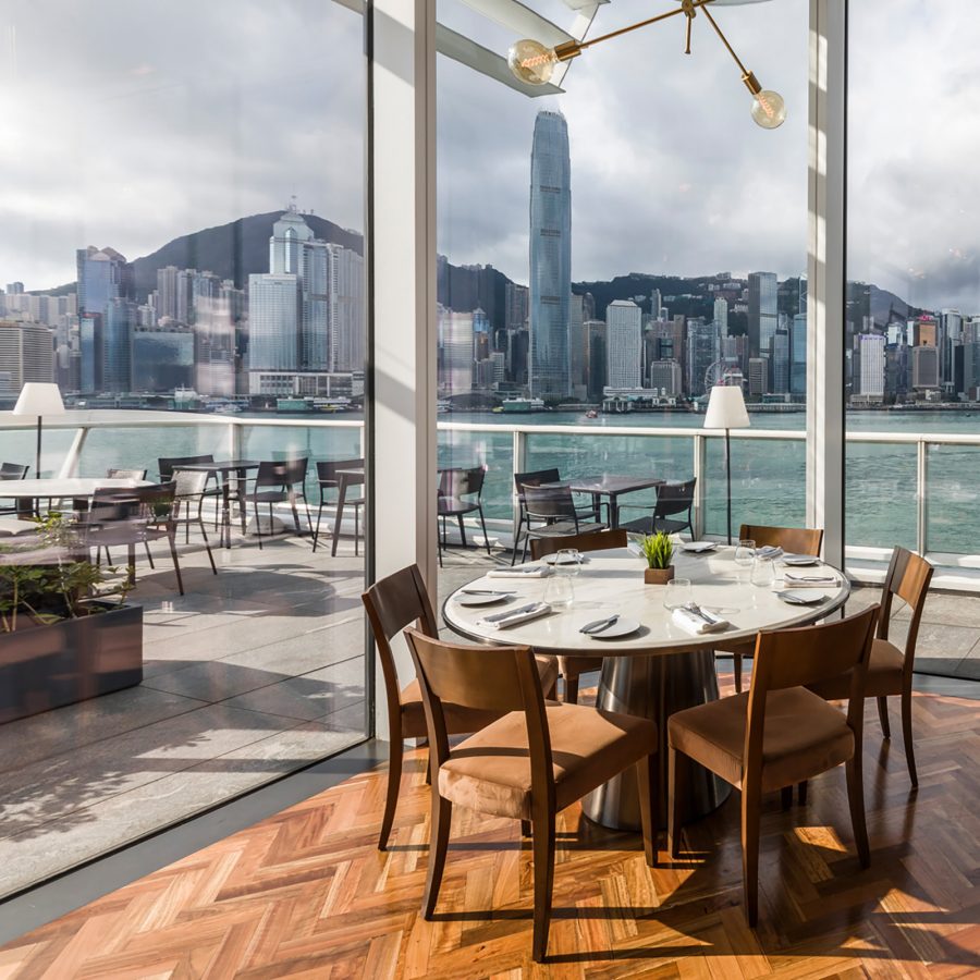 The exterior of Harbourside Grill includes outdoor seating directly facing the harbour and skyline of Hong Kong. 