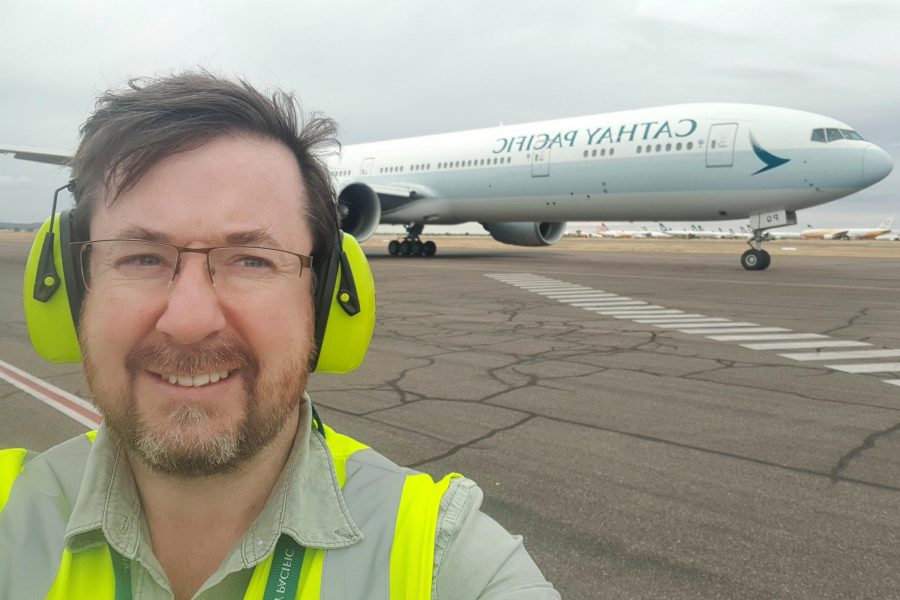 Benjamin Connell, Regional Engineering Manager Southwest Pacific in safety gear on airport tarmac with Cathay Pacific plane in background.