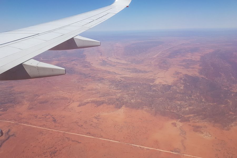 Wide panoramic shot of Alice Springs landscape with dramatic sky and aircraft wing