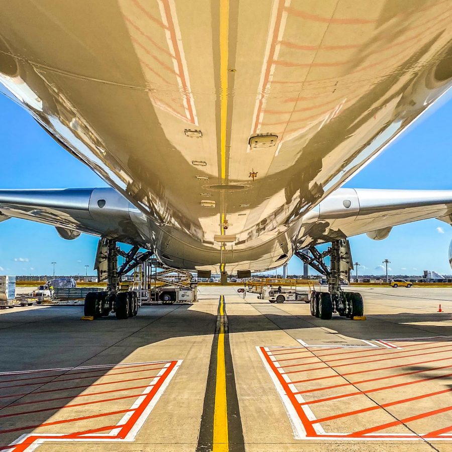 View from beneath a parked Cathay Pacific plane showing engines and landing gear.