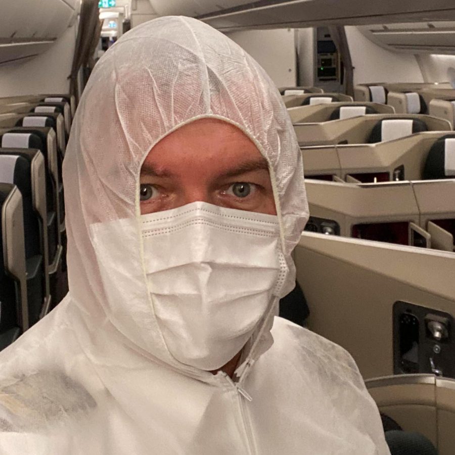 Individual in full protective gear inside an airplane cabin.