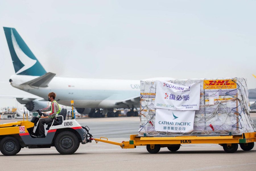 Worker towing vaccine cargo with Cathay Pacific plane in background