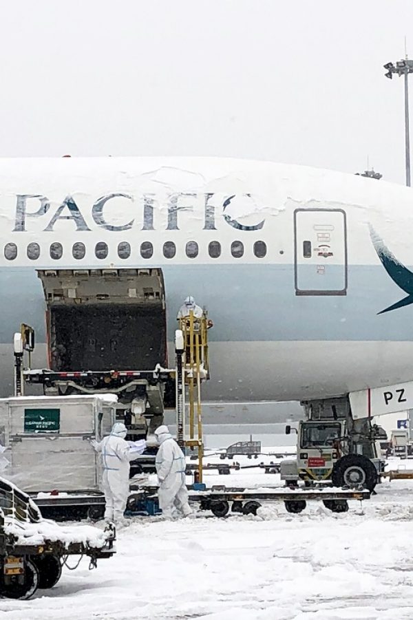 Cathay Pacific airplane being loaded with cargo in snowy weather.