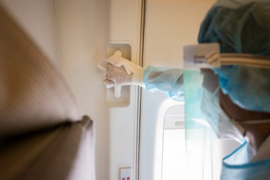 Person wearing protective gear cleaning the inside of an airplane.