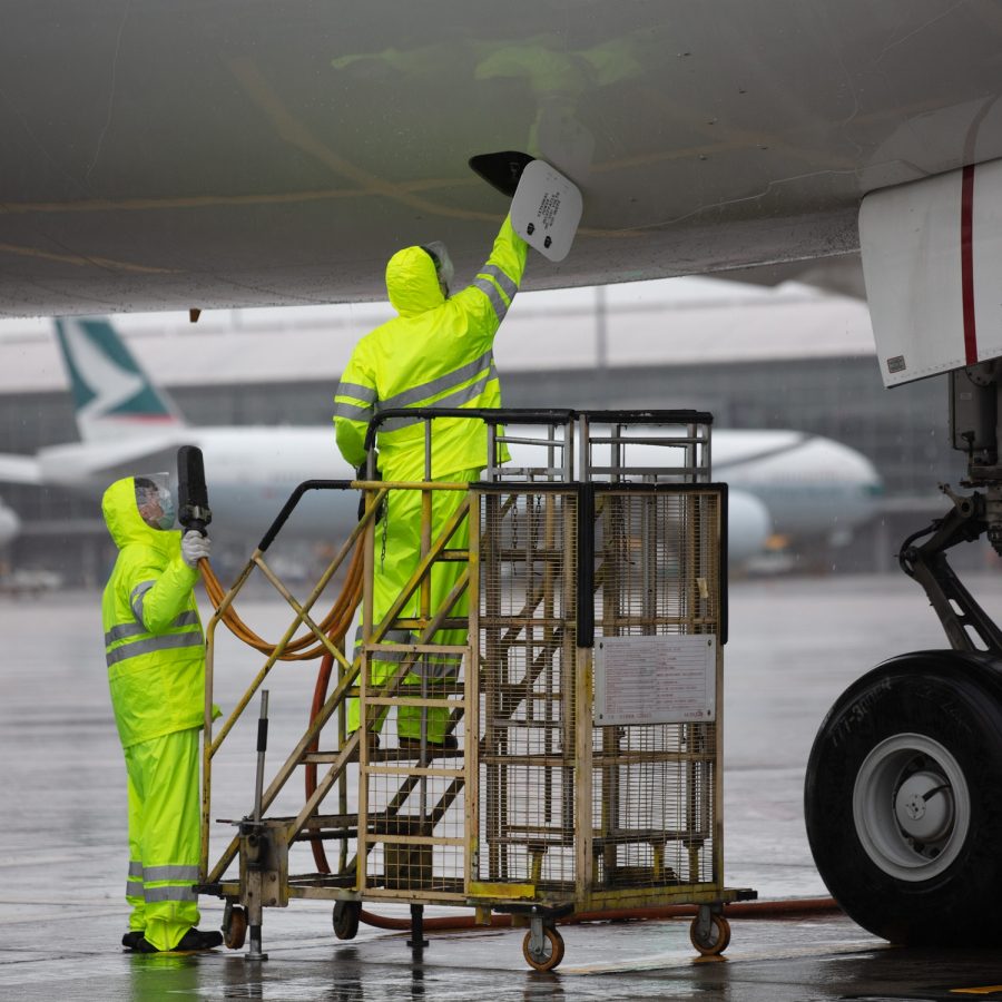Workers in yellow suits inspecting an airplane.