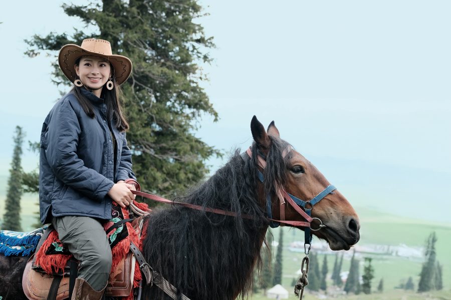A woman wearing a cowboy hat riding a horse.