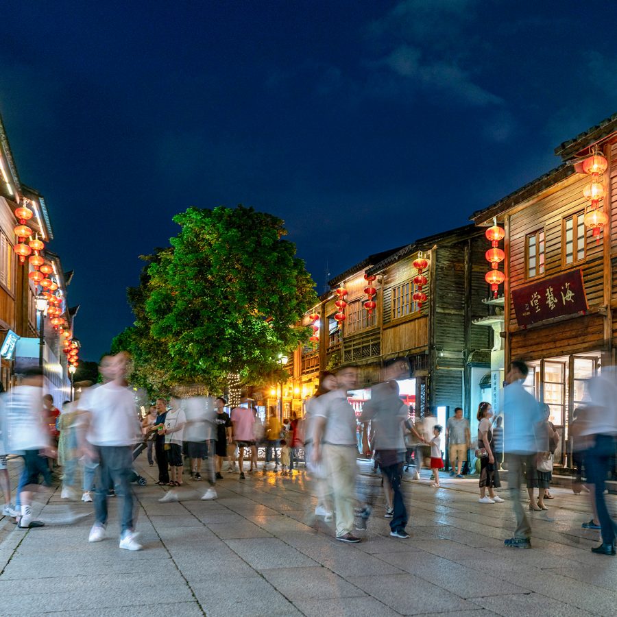 A motion blur shot of people walking on a sidewalk in Sanfang Qixiang at night. 