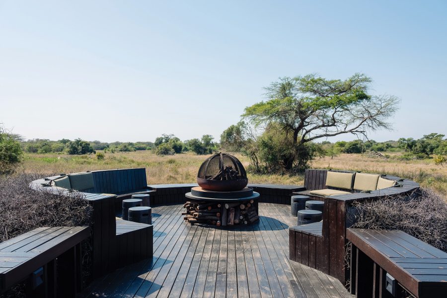 A wooden deck at Phinda Forest Lodge, with a fire pit in the middle and seating arranged around the edge.