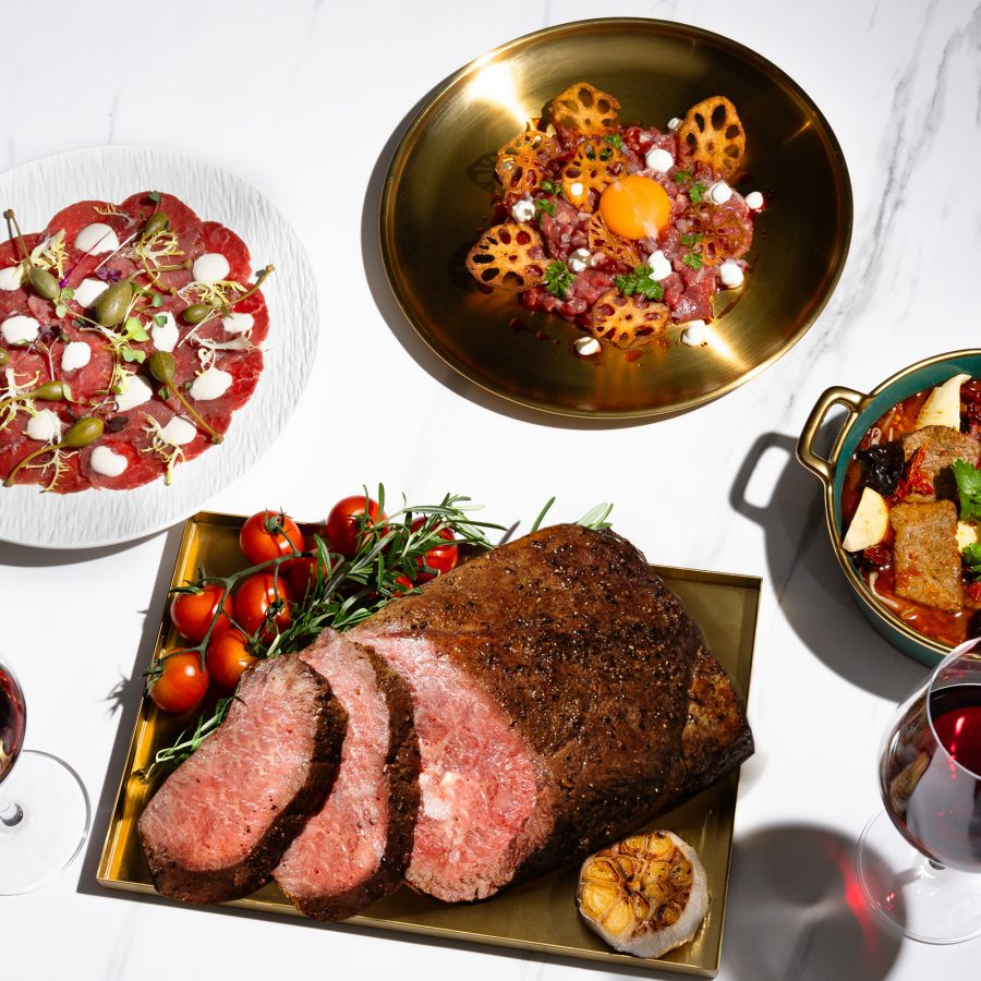 View of a series of plates served at Food Studio including Sichuan Wagyu and glasses of red wine.
