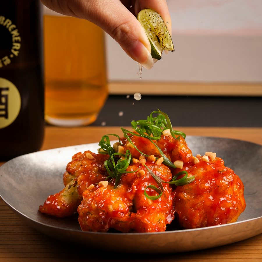 Person squeezing a lime wedge over Korean fried chicken at O’rm. 