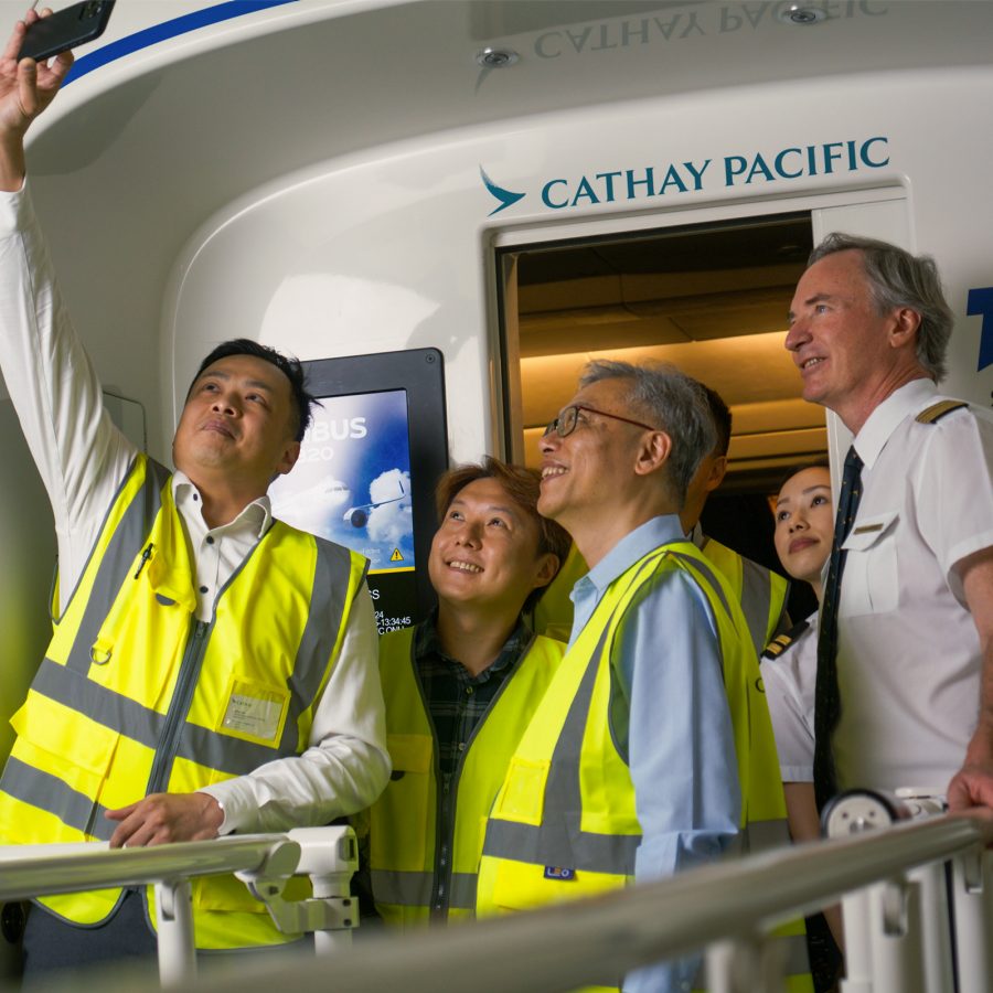 A group of staff take a congratulatory selfie outside a flight simulator.