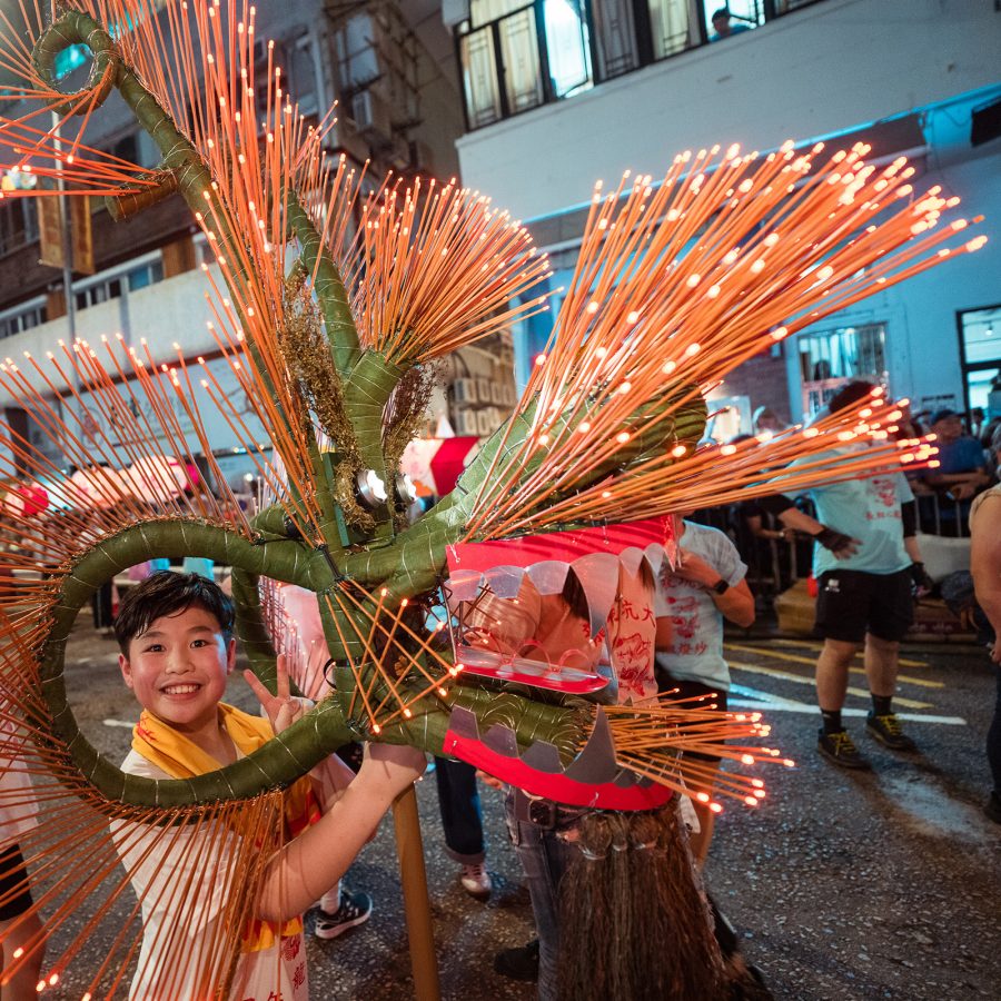 A boy smiles through the curls of the Tai Hang Fire Dragon during Mid-Autumn Festival.