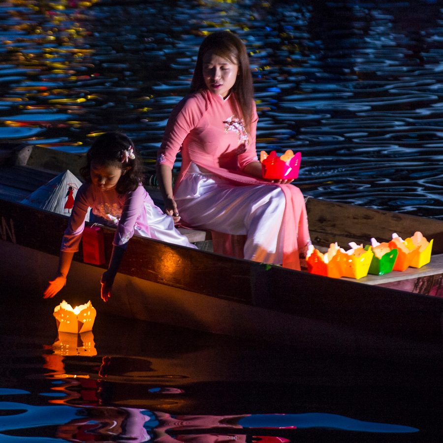 A woman and a little girl release colourful floating lanterns into the water in Vietnam during Tet Trung Thu. 