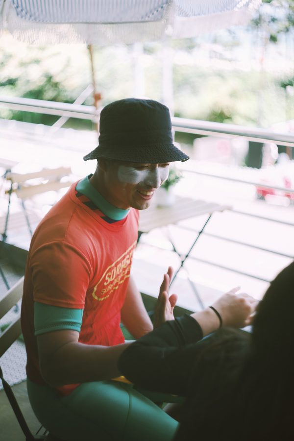 Surfgym founder Kyungsik Min sitting in the outdoor area of his shop, with sunscreen on his face. 