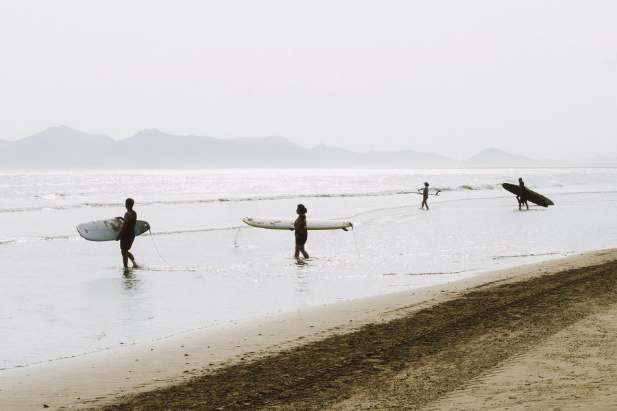 People walking out into the water with their surfboards on Dadaepo Beach.
