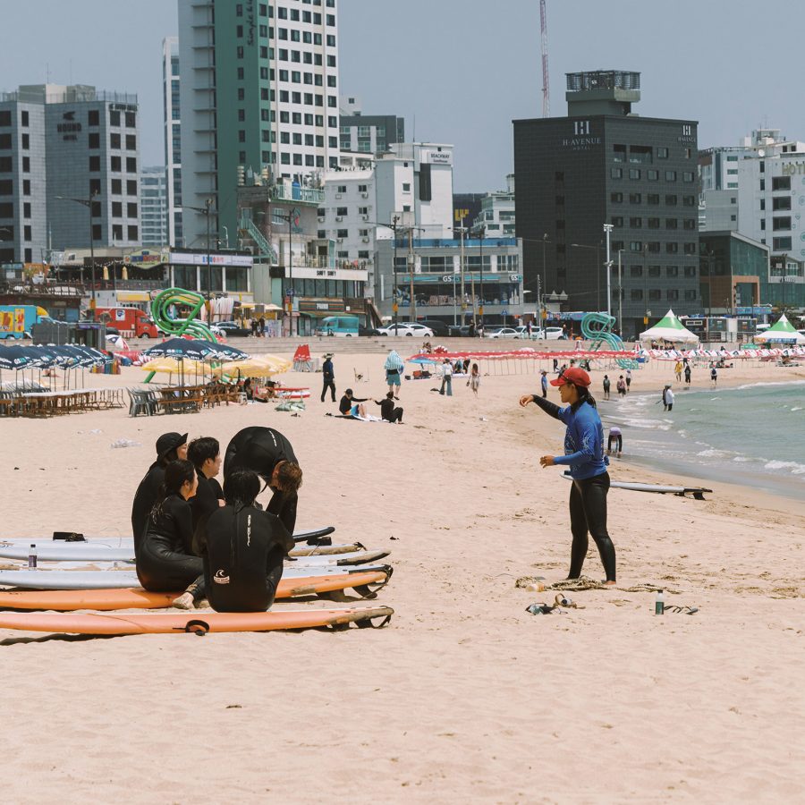 Surf Holic instructor Yeseul Park teaching a class on Songjeong Beach while her students sit on their surfboards.
