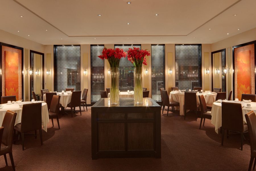 The interior of Imperial Treasure Super Peking Duck in Singapore, with tables, chairs, flower arrangements and floor-to-ceiling windows.