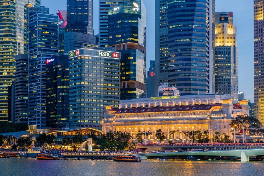 Exterior view of The Fullerton Hotel in Singapore and the surrounding Central Business District skyline at dusk.