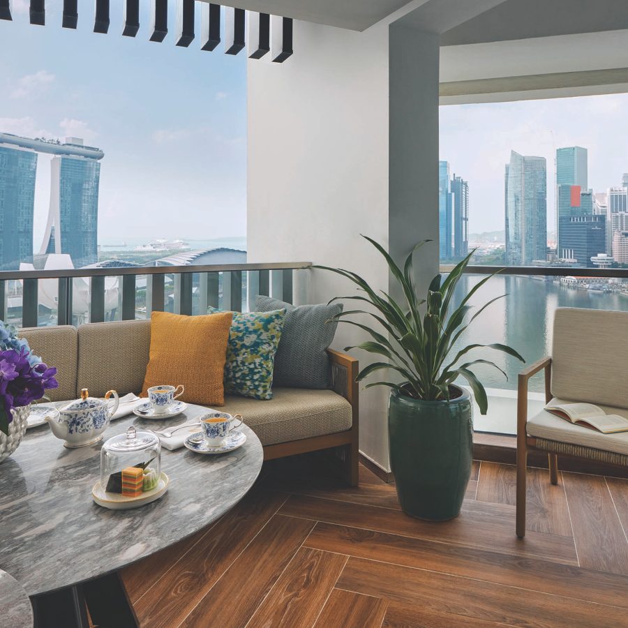 Open-air dining space on the balcony of Mandarin Oriental, Singapore and a view of the city skyline, including the iconic Marina Bay Sands hotel in the background.