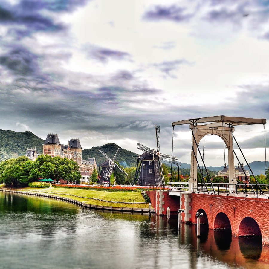 A quaint, scenic landscape including a canal, castle and windmill at Huis Ten Bosch.