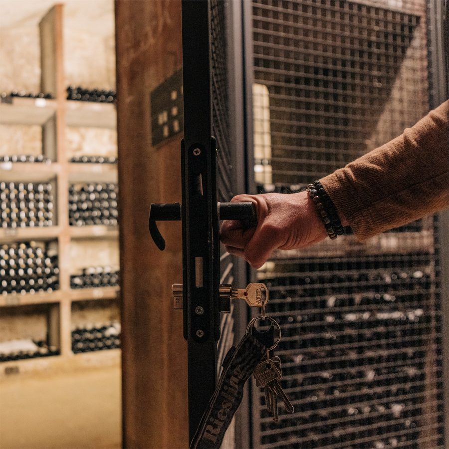 A hand holding a door open to the Schloss Vollrads wine cellar.