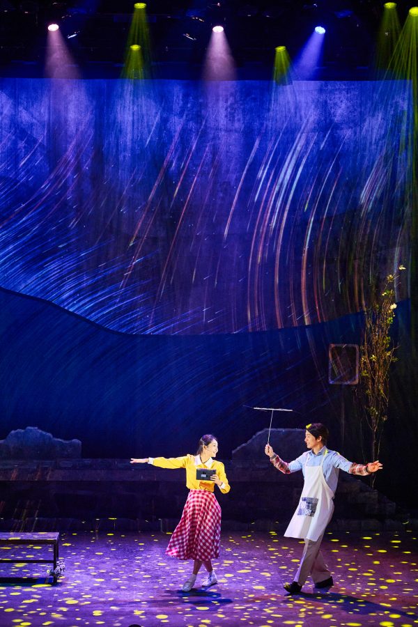 A woman and a man smiling and dancing on stage. 