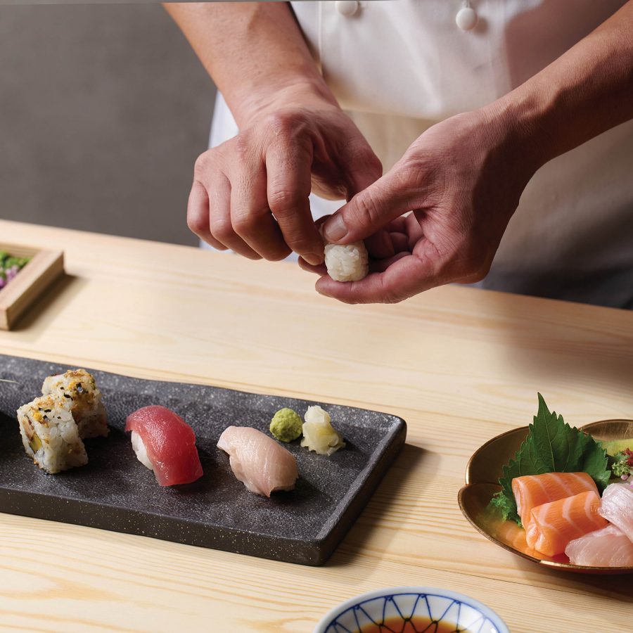 Close-up of a sushi chef preparing a selection of cold dishes.
