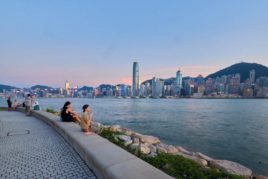 A skyline view of Victoria Harbour by the WestK promenade during blue hour.