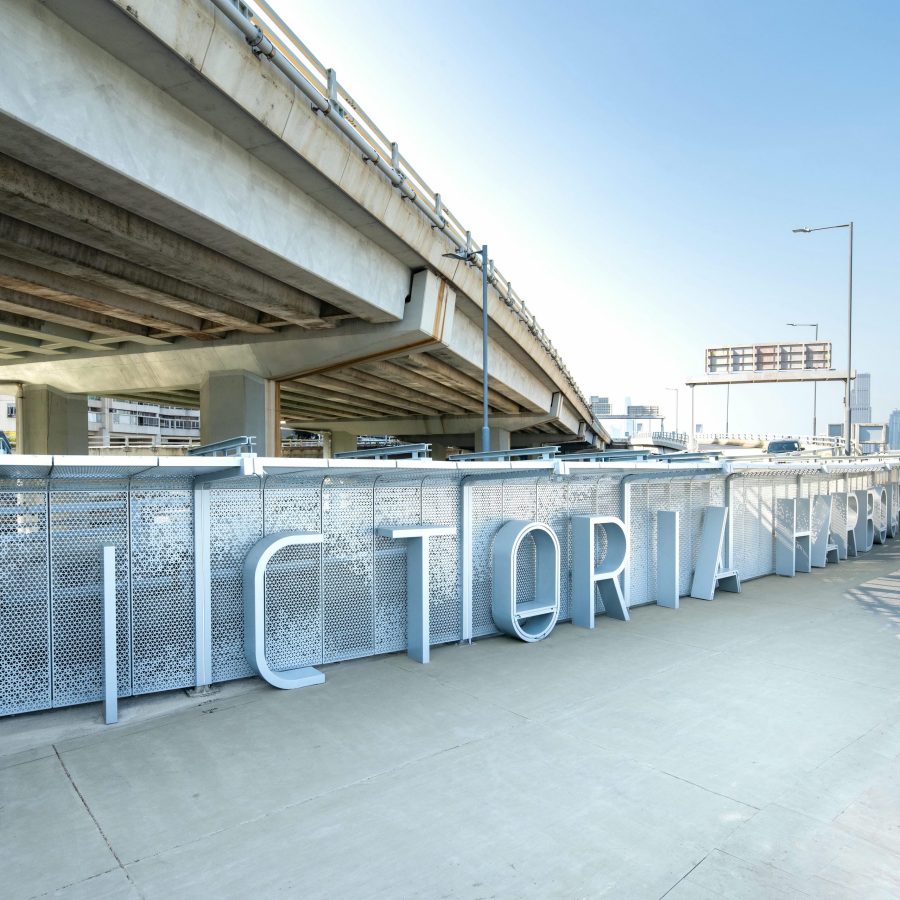 A wide paved walking and running path on the East Coast Boardwalk by Victoria Harbour, with a highway running alongside it.
