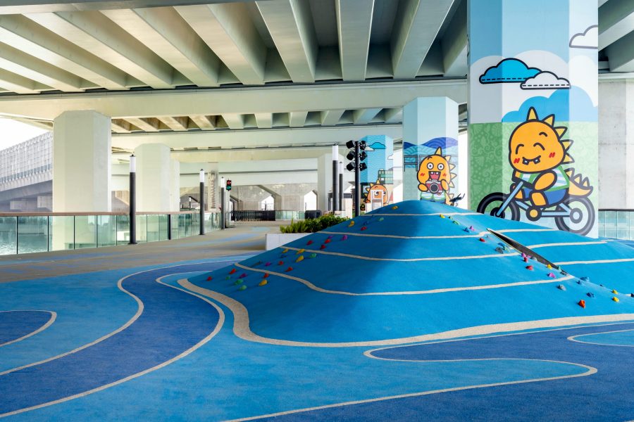 An area under the bridge of the East Coast Boardwalk, with various kid-friendly playground equipment.